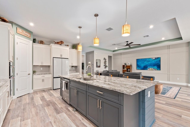 kitchen with a sink, ceiling fan, light wood-type flooring, and white cabinets