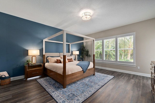 bedroom featuring a textured ceiling, baseboards, and dark wood finished floors