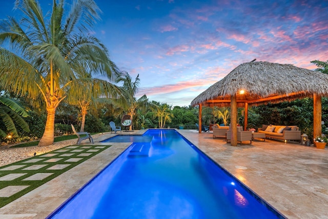pool at dusk featuring outdoor lounge area, a patio area, a gazebo, and an outdoor pool