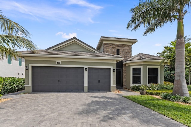 view of front of property with a tile roof, a garage, stucco siding, and decorative driveway