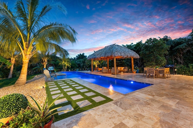 pool at dusk featuring a grill, a patio, an outdoor pool, an outdoor hangout area, and a gazebo
