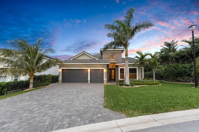 view of front of house featuring fence, an attached garage, a yard, stucco siding, and decorative driveway