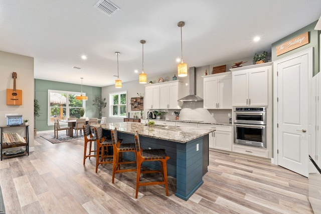 kitchen featuring recessed lighting, black electric stovetop, visible vents, wall chimney range hood, and double oven