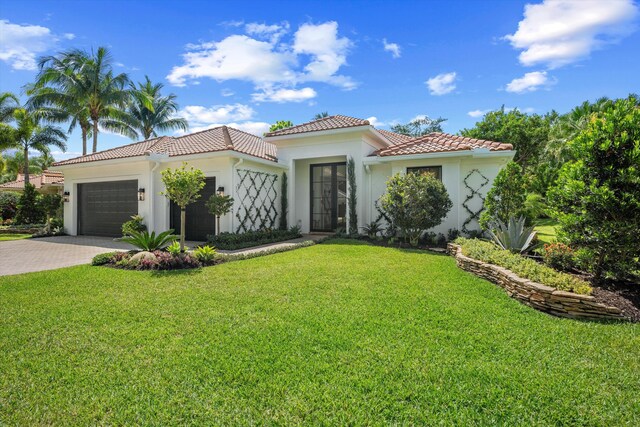 mediterranean / spanish-style home featuring a tiled roof, stucco siding, an attached garage, and decorative driveway