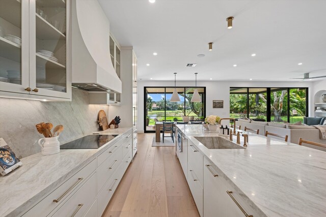 kitchen with custom exhaust hood, black electric cooktop, a sink, recessed lighting, and healthy amount of natural light