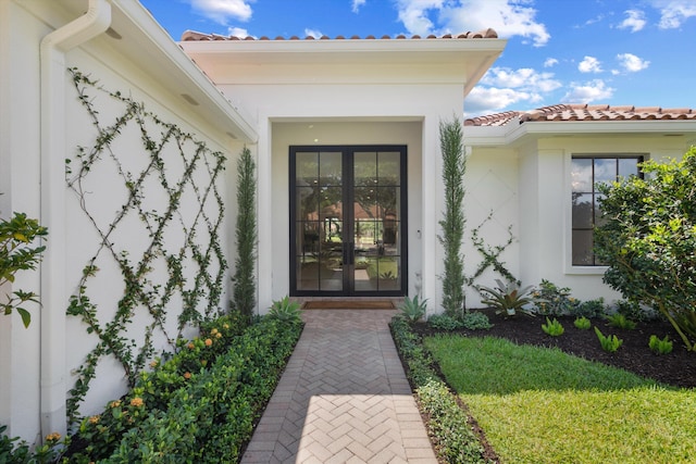 doorway to property with a tiled roof, stucco siding, and french doors