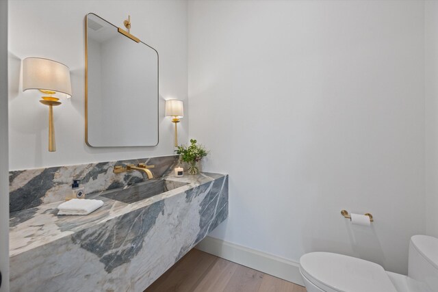 bathroom with toilet, a sink, wood finished floors, and baseboards
