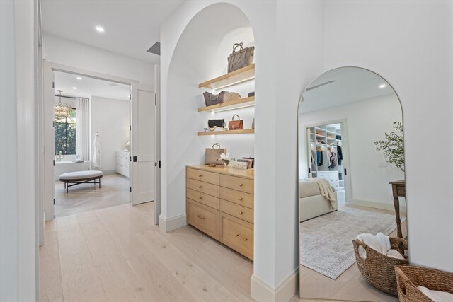 corridor featuring light wood-style floors, arched walkways, and recessed lighting