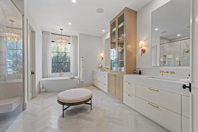 bathroom with a chandelier, a stall shower, baseboards, two vanities, and recessed lighting