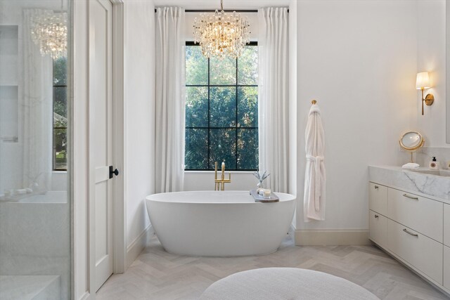 bathroom featuring a chandelier, baseboards, a soaking tub, and vanity
