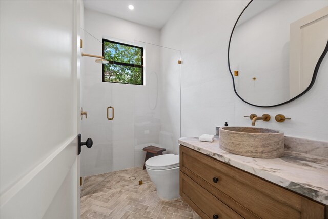 bathroom featuring a shower stall, toilet, vanity, and brick patterned floors