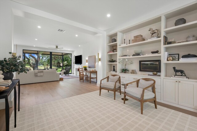 sitting room with light wood-style flooring, recessed lighting, ceiling fan, and built in shelves