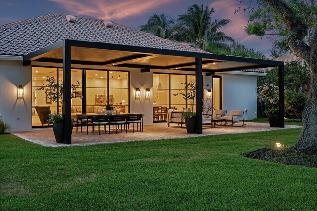 back of property at dusk featuring a patio area, a yard, and an outdoor hangout area