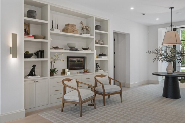 sitting room with baseboards, built in shelves, and recessed lighting