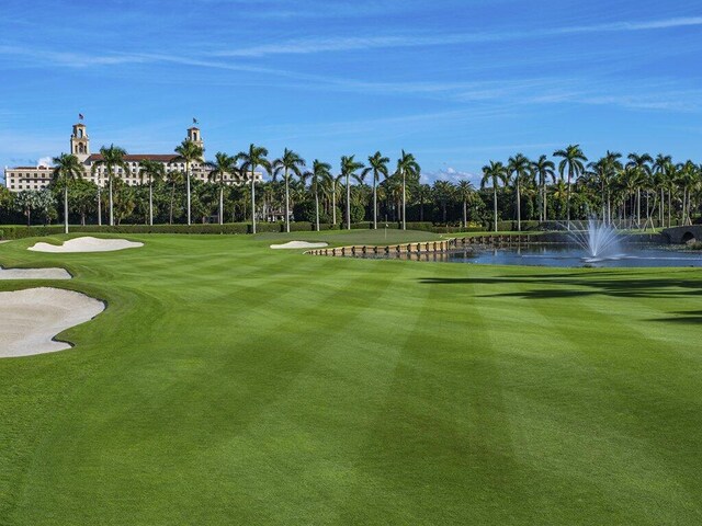 view of home's community featuring golf course view, a water view, and a lawn