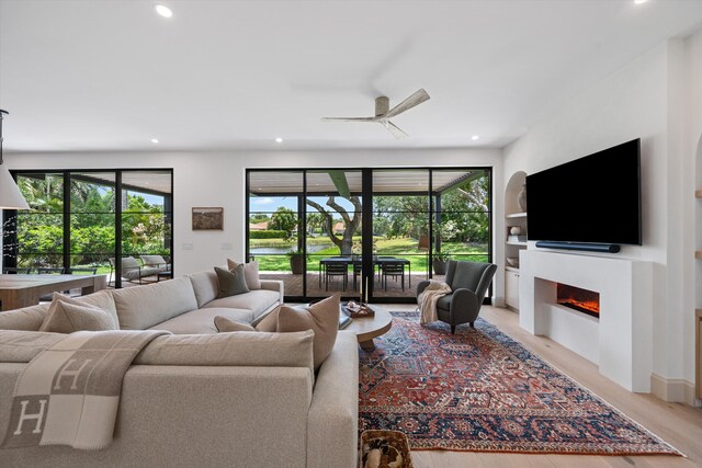 living room featuring plenty of natural light, recessed lighting, a glass covered fireplace, light wood-style floors, and ceiling fan