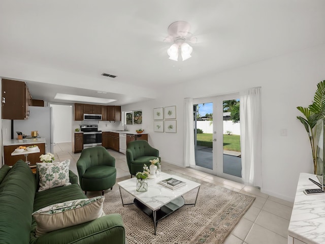 living room with light tile patterned floors, baseboards, a water view, and ceiling fan