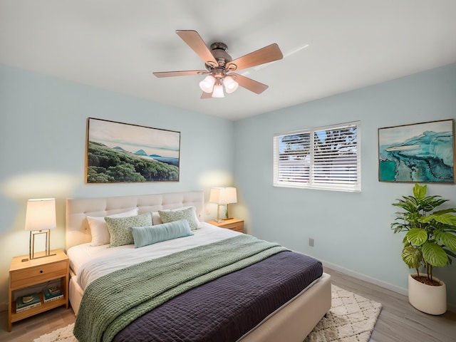 bedroom featuring light wood-type flooring, baseboards, and a ceiling fan