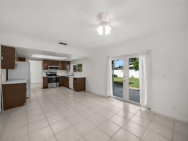 kitchen with appliances with stainless steel finishes, light countertops, a sink, baseboards, and dark brown cabinetry