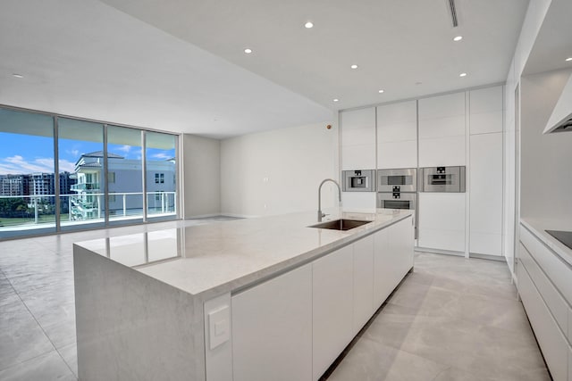 220 SE Mizner Blvd Unit Ph920, Boca Raton, FL 33432 - kitchen with a sink, modern cabinets, white cabinets, a large island with sink, and a wall of windows