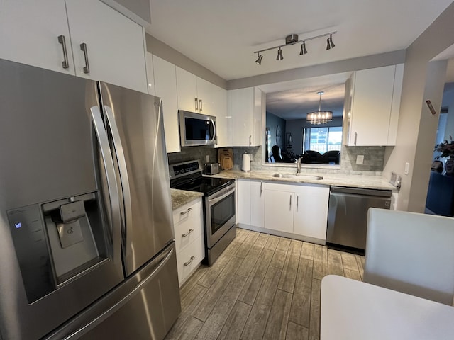 7340 Amberly Ln # 205, Delray Beach, FL 33446 - kitchen with a sink, light wood-style flooring, white cabinetry, backsplash, and appliances with stainless steel finishes
