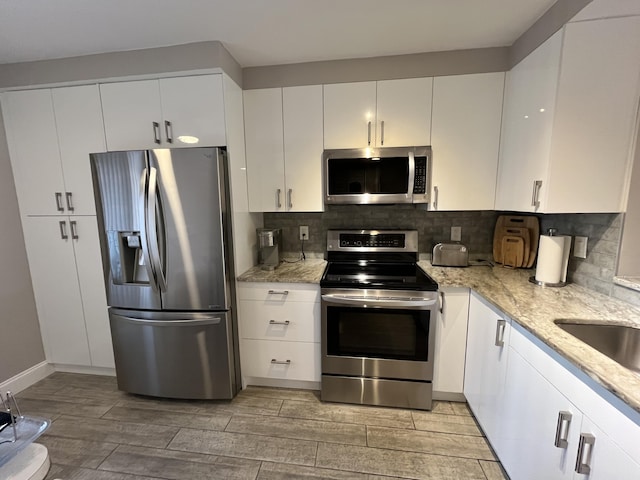 7340 Amberly Ln # 205, Delray Beach, FL 33446 - kitchen with light stone counters, stainless steel appliances, tasteful backsplash, and light wood-style flooring