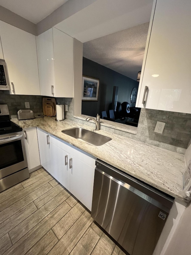 7340 Amberly Ln # 205, Delray Beach, FL 33446 - kitchen with a sink, stainless steel appliances, white cabinetry, and tasteful backsplash
