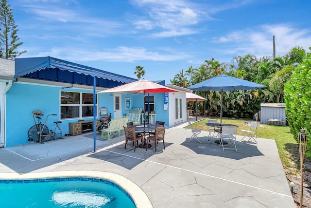 654 Bunting Dr, Delray Beach, FL 33444 - exterior space with an outbuilding, outdoor dining space, a patio area, stucco siding, and a storage unit