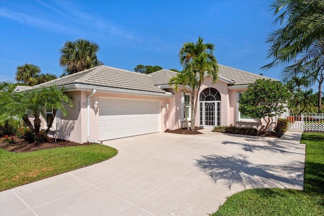 4922 SE Heartleaf Ter, Hobe Sound, FL 33455 - view of front facade with a garage, concrete driveway, stucco siding, a tile roof, and fence
