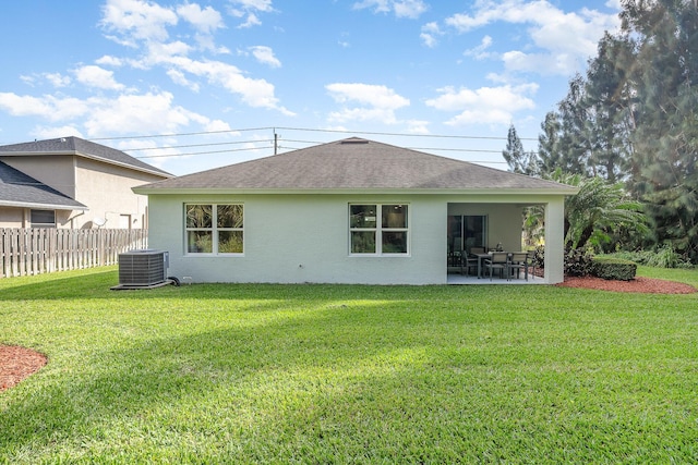 356 SW Prima Vista Blvd, Port Saint Lucie, FL 34953 - rear view of house featuring roof with shingles, fence, central AC, a patio, and a lawn