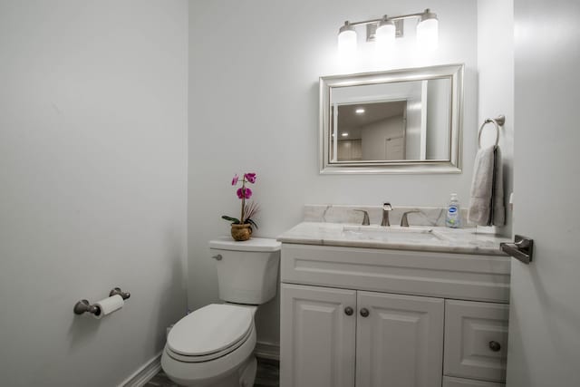 half bath featuring toilet, baseboards, and vanity