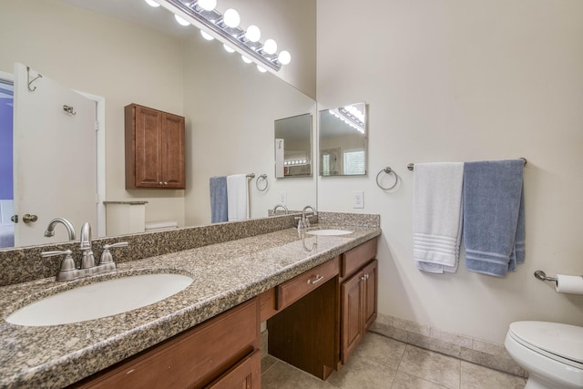 bathroom with toilet, tile patterned flooring, baseboards, and a sink