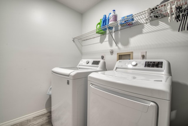 clothes washing area with baseboards, separate washer and dryer, laundry area, and wood finished floors