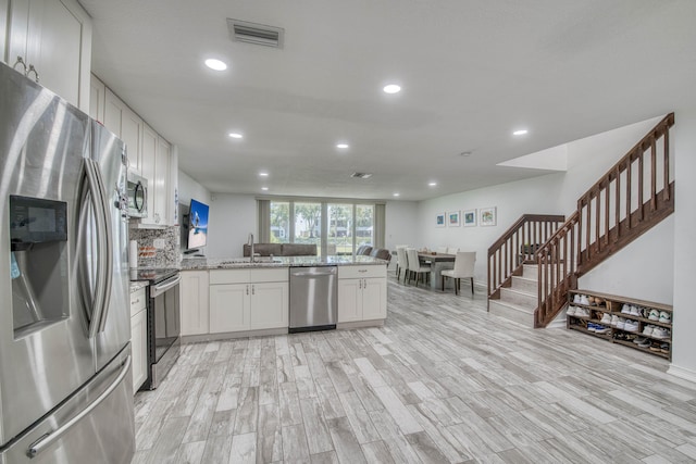 kitchen featuring recessed lighting, a peninsula, appliances with stainless steel finishes, and a sink