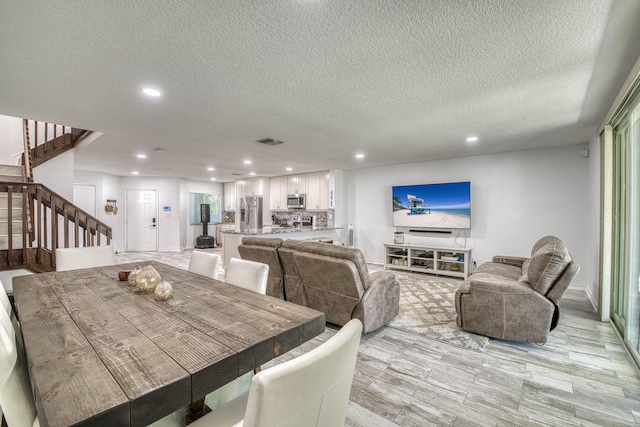 dining room featuring stairway, visible vents, recessed lighting, and a textured ceiling