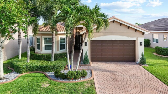 view of front of house featuring an attached garage, decorative driveway, stucco siding, and a front lawn
