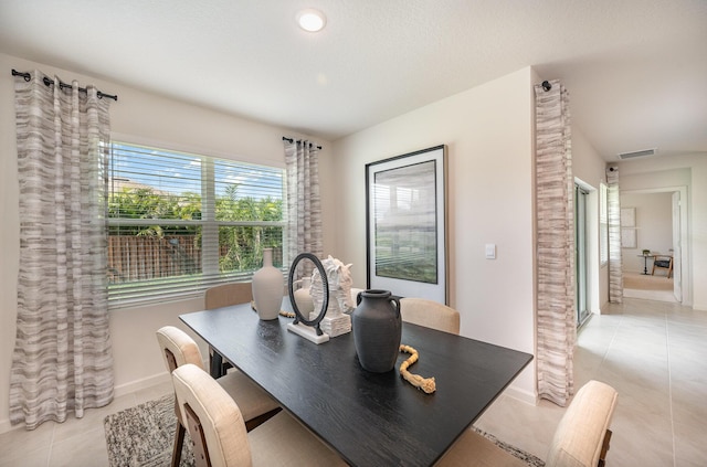 dining space featuring light tile patterned floors, visible vents, and baseboards