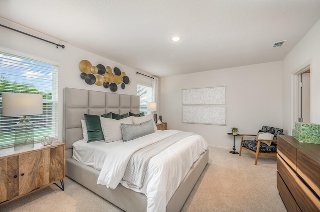 bedroom with baseboards, light carpet, and visible vents