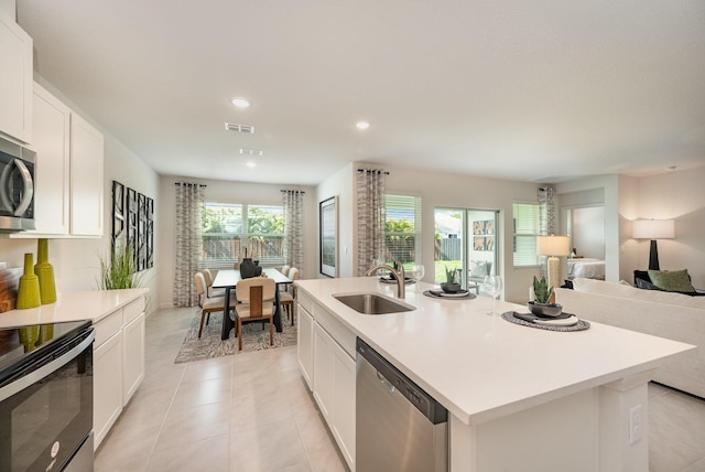 kitchen featuring a sink, stainless steel appliances, open floor plan, and white cabinets
