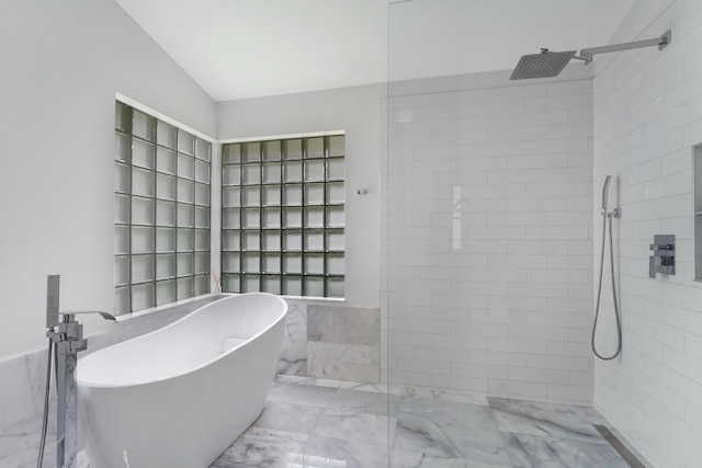 full bath featuring lofted ceiling, marble finish floor, a freestanding tub, and a walk in shower
