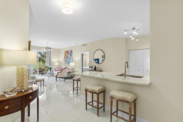 250 NE 3rd Ave Unit 1308, Delray Beach, FL 33444 - kitchen with light stone countertops, a breakfast bar area, light tile patterned floors, a sink, and a chandelier