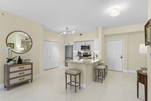 250 NE 3rd Ave Unit 1308, Delray Beach, FL 33444 - kitchen with a peninsula, stainless steel appliances, a breakfast bar, light countertops, and baseboards