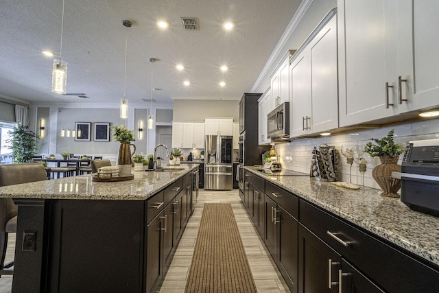 kitchen featuring a breakfast bar, a sink, white cabinets, backsplash, and appliances with stainless steel finishes