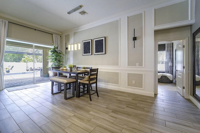 dining area with crown molding, a healthy amount of sunlight, wood tiled floor, and visible vents