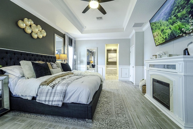 bedroom featuring a tray ceiling, visible vents, and wood finished floors