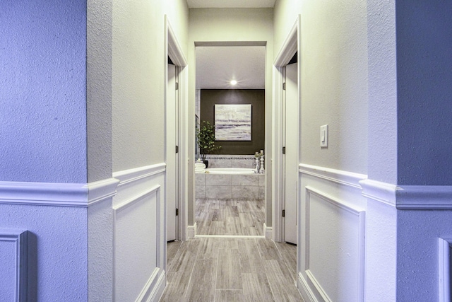 hall with a textured wall and wood finished floors
