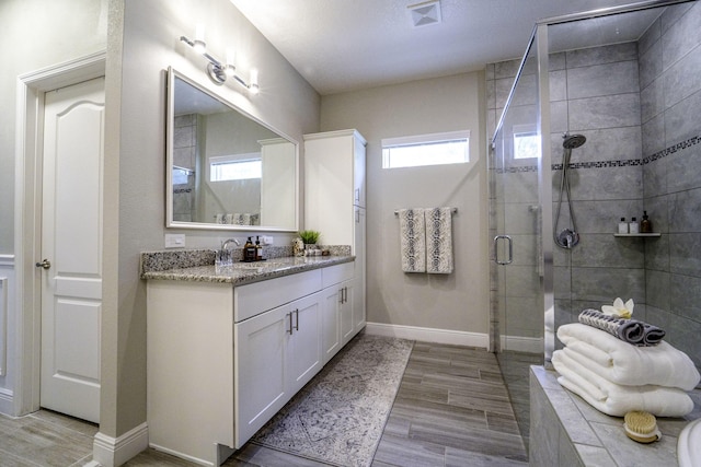 full bathroom with wood finished floors, visible vents, baseboards, a shower stall, and vanity