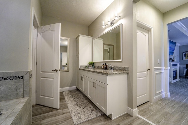 full bath with vanity, a wainscoted wall, and wood finished floors