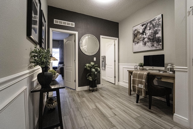6920 NW Jorgensen Rd, Port Saint Lucie, FL 34983 - office area featuring a textured ceiling, light wood finished floors, a wainscoted wall, and a textured wall