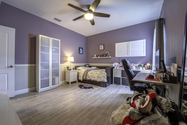 bedroom featuring light wood finished floors, visible vents, baseboards, and a ceiling fan